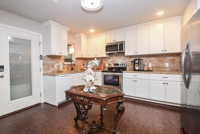 kitchen with tasteful backsplash, appliances with stainless steel finishes, white cabinetry, and light stone counters