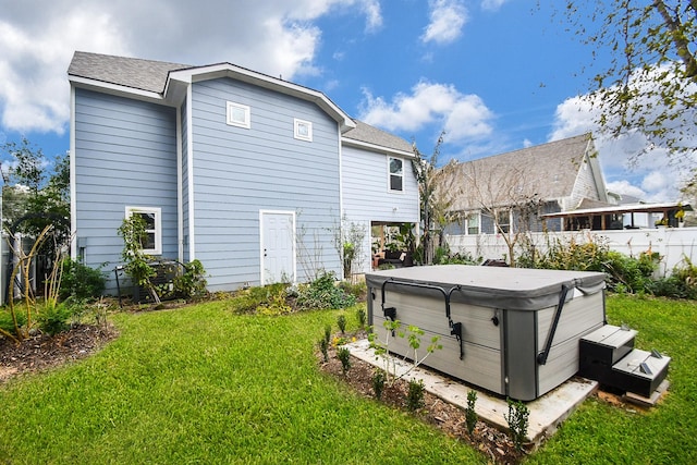 back of house featuring a hot tub and a lawn