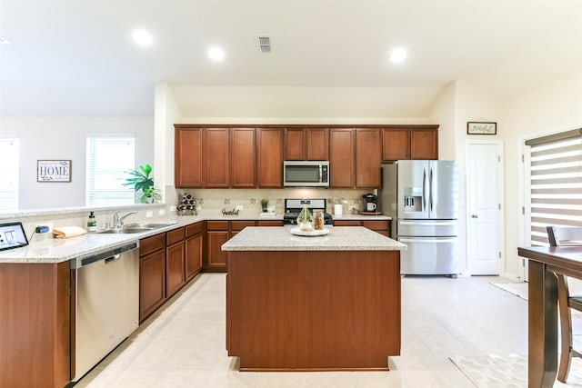 kitchen featuring vaulted ceiling, a center island, sink, stainless steel appliances, and light stone counters