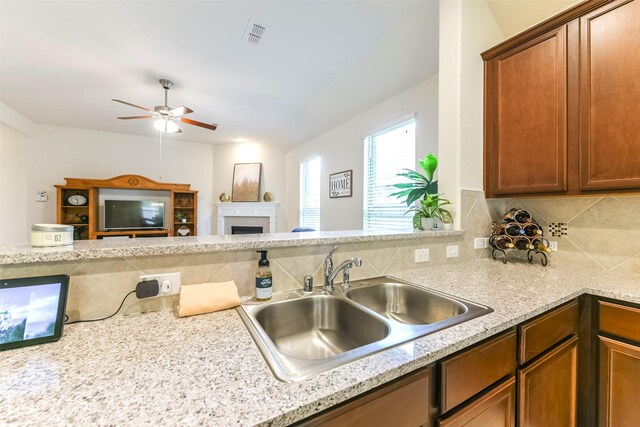 kitchen featuring light stone countertops, ceiling fan, tasteful backsplash, and sink