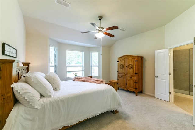 bedroom featuring light carpet, ceiling fan, lofted ceiling, and ensuite bath