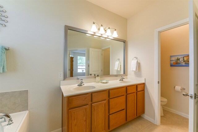 bathroom featuring toilet, tile patterned floors, a bath, and vanity