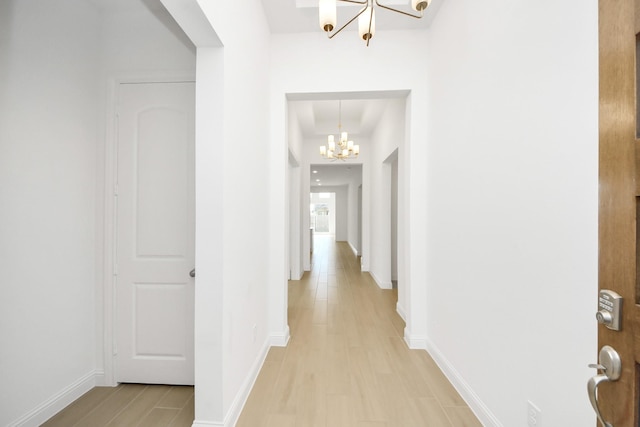 hallway featuring a notable chandelier and light wood-type flooring