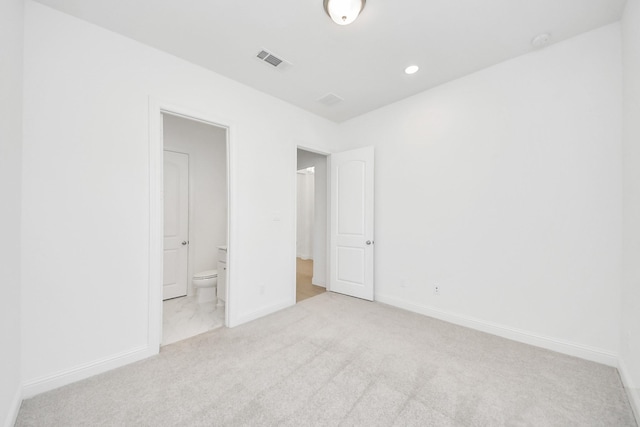 unfurnished bedroom featuring light colored carpet and ensuite bath