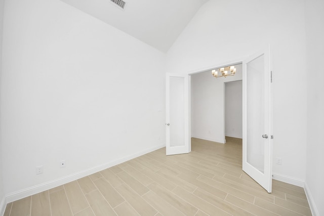 empty room with an inviting chandelier, lofted ceiling, and french doors