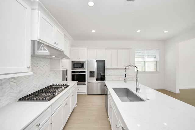 kitchen featuring appliances with stainless steel finishes, white cabinetry, light stone counters, and sink