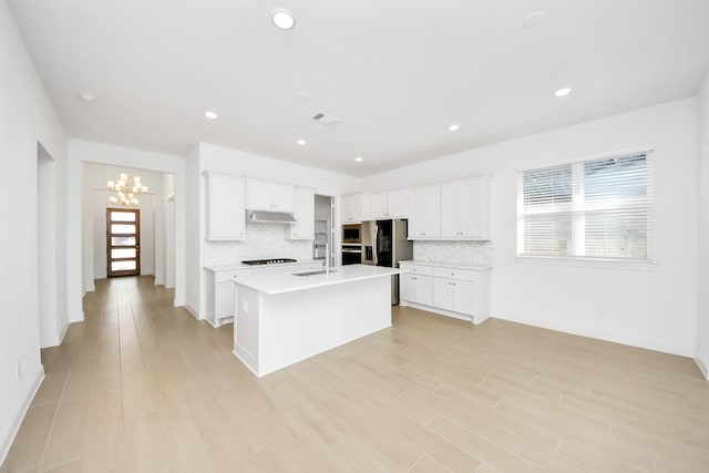 kitchen featuring black gas cooktop, white cabinets, tasteful backsplash, and a kitchen island with sink