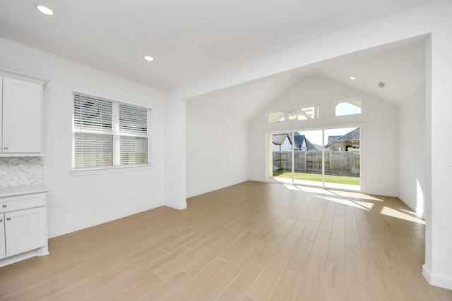 unfurnished living room with vaulted ceiling, ceiling fan, and light hardwood / wood-style flooring