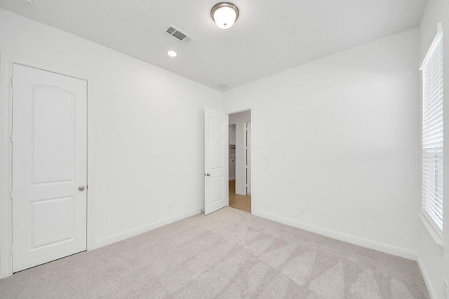 unfurnished bedroom with light colored carpet and a closet