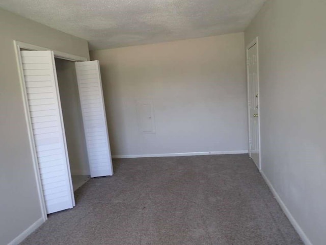 unfurnished bedroom featuring a closet, dark carpet, and a textured ceiling