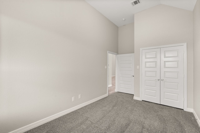 unfurnished bedroom featuring a closet, carpet flooring, and high vaulted ceiling