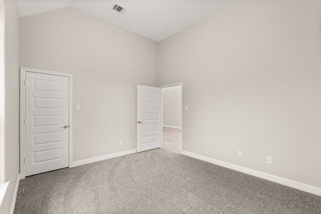 empty room with high vaulted ceiling and carpet floors