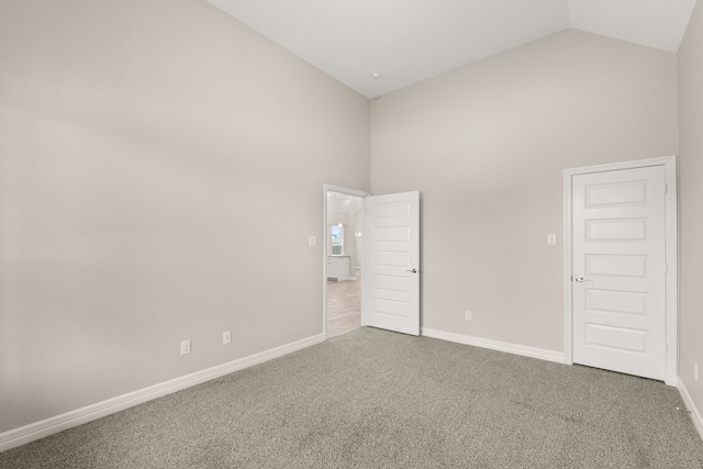 unfurnished bedroom with carpet and high vaulted ceiling