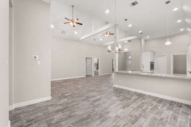 unfurnished living room featuring high vaulted ceiling, ceiling fan, and sink