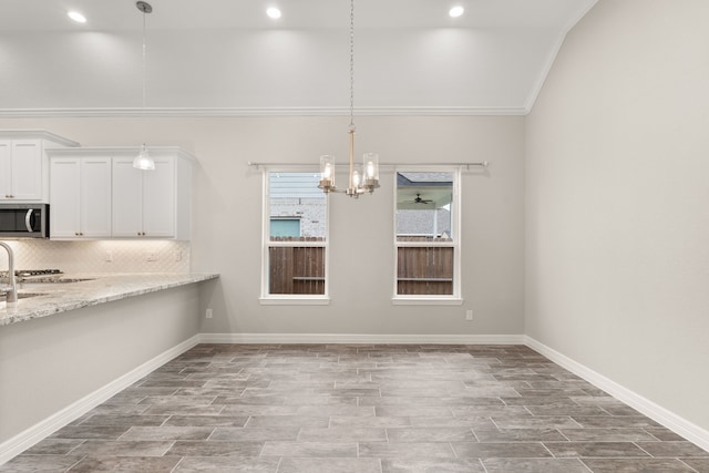 unfurnished dining area featuring vaulted ceiling, ornamental molding, and a notable chandelier