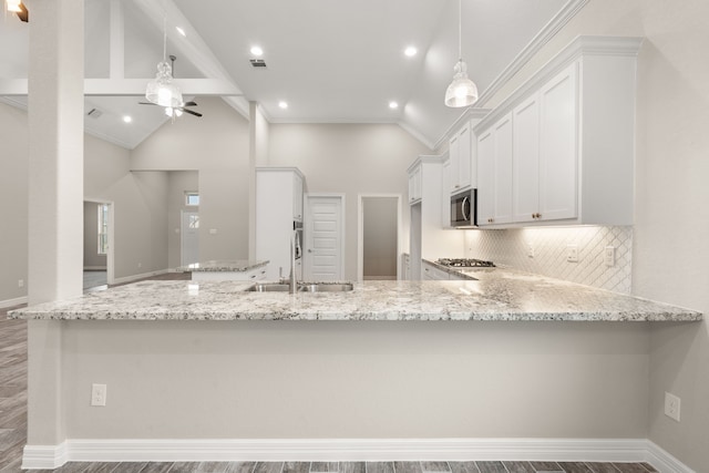 kitchen featuring kitchen peninsula, decorative backsplash, sink, white cabinets, and light stone counters