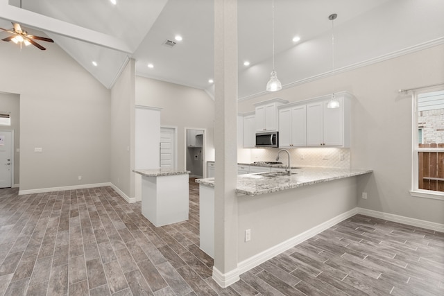 kitchen with white cabinetry, ceiling fan, sink, kitchen peninsula, and high vaulted ceiling