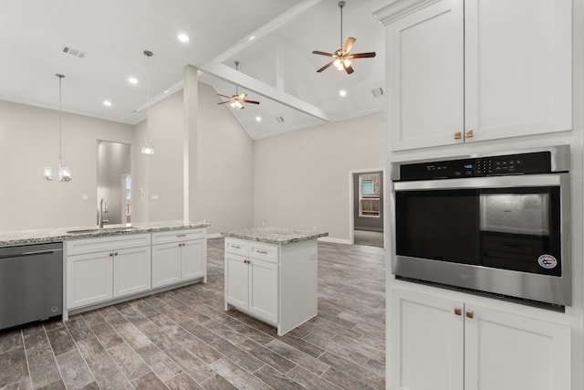 kitchen featuring light stone countertops, dishwashing machine, a kitchen island, sink, and oven