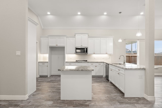 kitchen with light stone countertops, pendant lighting, white cabinetry, stainless steel appliances, and sink