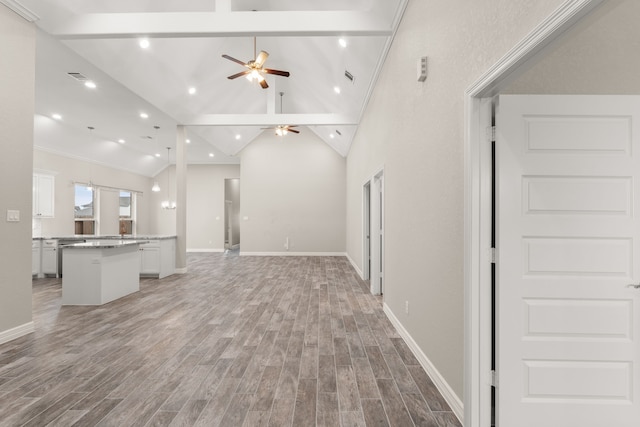 unfurnished living room with hardwood / wood-style flooring, ceiling fan, high vaulted ceiling, ornamental molding, and beam ceiling