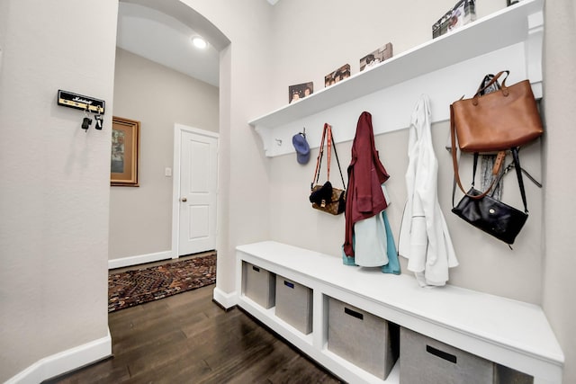 mudroom with arched walkways, dark wood-style flooring, and baseboards