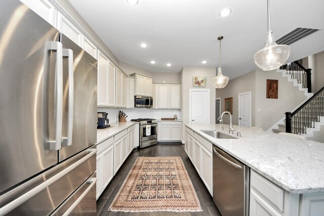 kitchen with a spacious island, decorative light fixtures, dark wood-type flooring, stainless steel appliances, and light stone counters