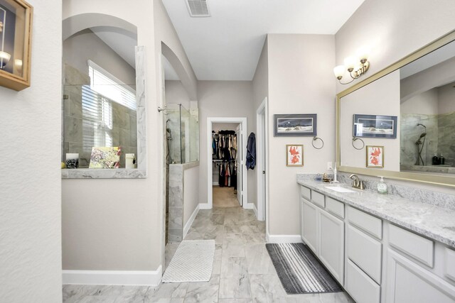 bathroom with tiled shower and vanity