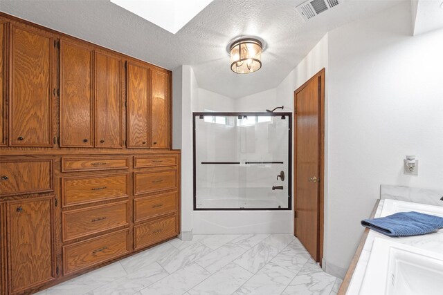 bathroom featuring a textured ceiling and bath / shower combo with glass door