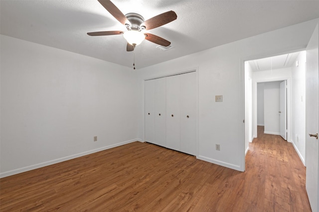 unfurnished bedroom with ceiling fan, a closet, and hardwood / wood-style flooring