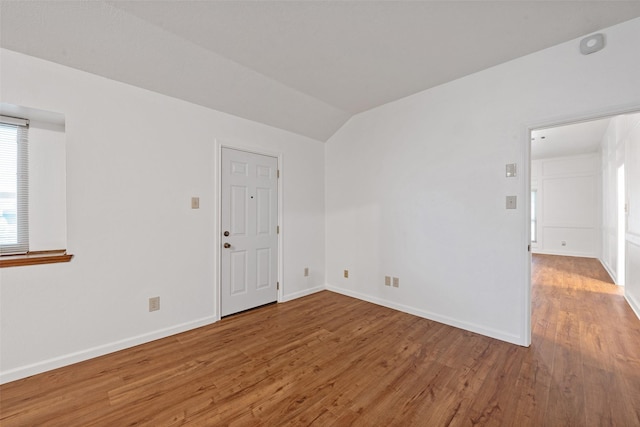 empty room with vaulted ceiling and wood-type flooring