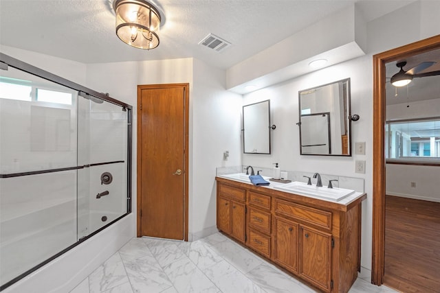 bathroom featuring a textured ceiling, ceiling fan, enclosed tub / shower combo, and vanity