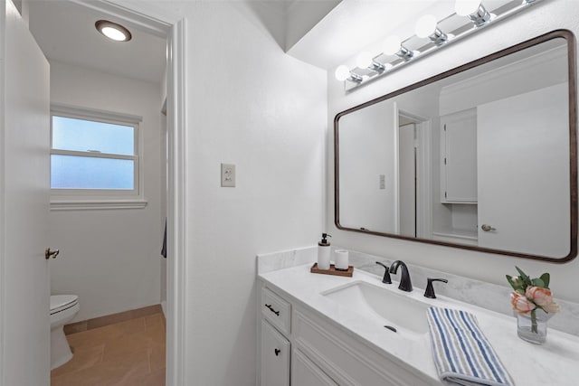 bathroom with toilet, vanity, and tile patterned floors