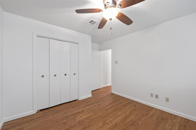 unfurnished bedroom with ceiling fan, hardwood / wood-style floors, and a closet