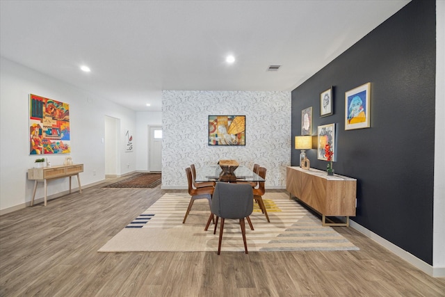 dining area featuring recessed lighting, an accent wall, visible vents, baseboards, and light wood-style floors