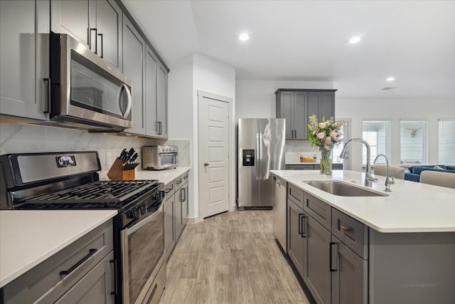 kitchen featuring light countertops, appliances with stainless steel finishes, gray cabinets, and a sink