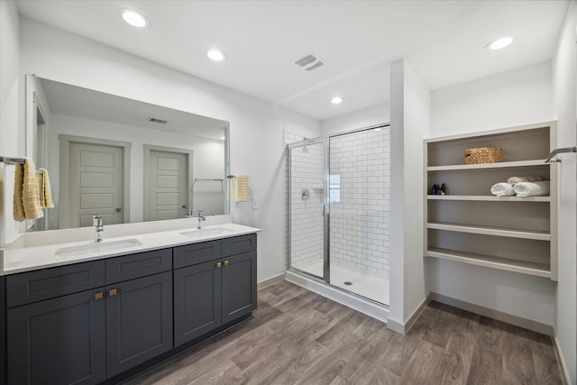 full bath featuring a stall shower, visible vents, a sink, and wood finished floors