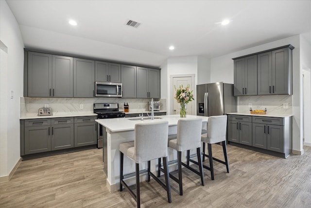 kitchen with decorative backsplash, gray cabinetry, and stainless steel appliances