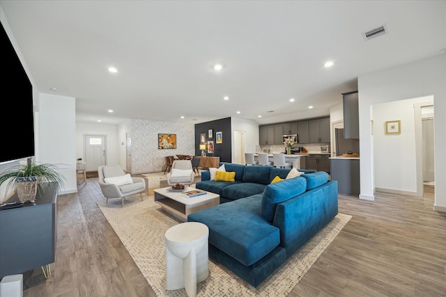 living area featuring baseboards, light wood-style floors, and recessed lighting