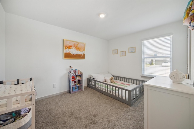 bedroom featuring carpet floors, a nursery area, and baseboards