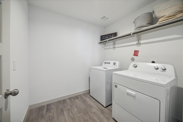 laundry area with light wood-style flooring, laundry area, visible vents, baseboards, and washing machine and clothes dryer