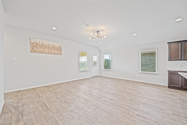 unfurnished living room with an inviting chandelier and light hardwood / wood-style flooring