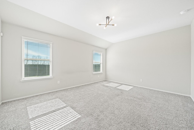 carpeted empty room with vaulted ceiling, a healthy amount of sunlight, and a notable chandelier