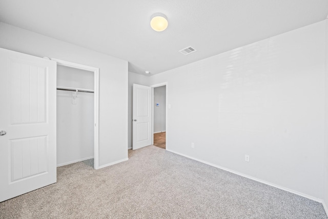 unfurnished bedroom featuring light colored carpet and a closet