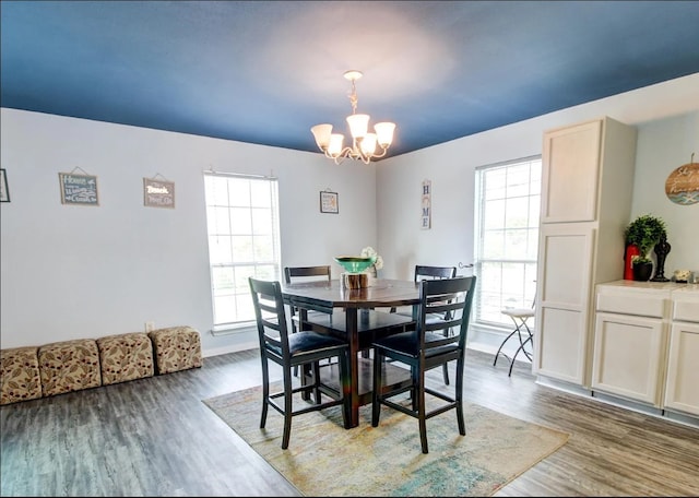 dining area with dark wood-type flooring and a notable chandelier