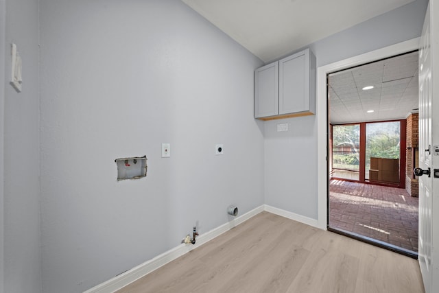 clothes washing area featuring hookup for a gas dryer, light hardwood / wood-style floors, hookup for a washing machine, hookup for an electric dryer, and cabinets