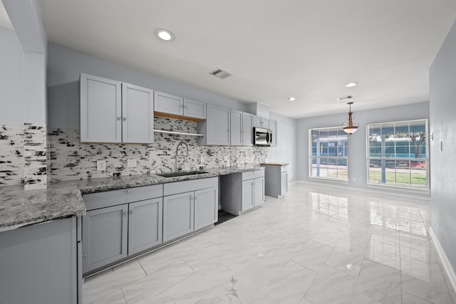 kitchen featuring sink, pendant lighting, gray cabinets, and tasteful backsplash