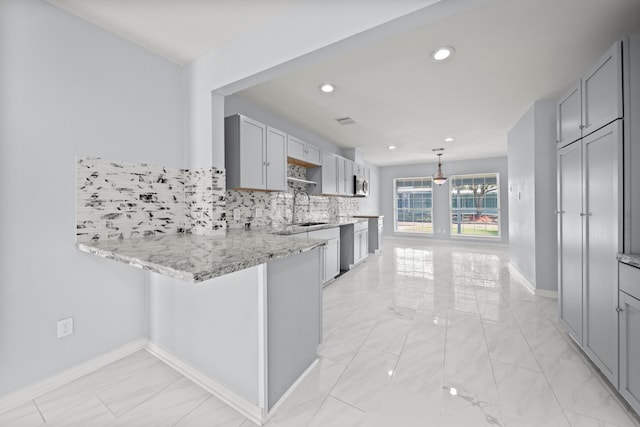 kitchen with backsplash, kitchen peninsula, sink, hanging light fixtures, and gray cabinetry