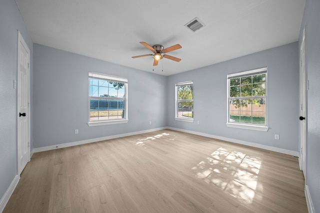 empty room with ceiling fan, a wealth of natural light, and light wood-type flooring