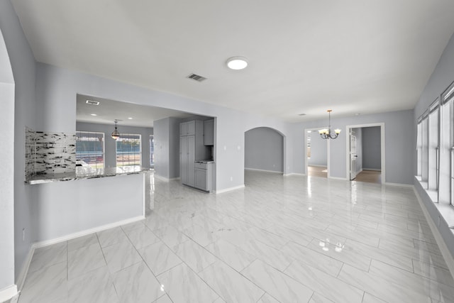 unfurnished living room featuring a chandelier