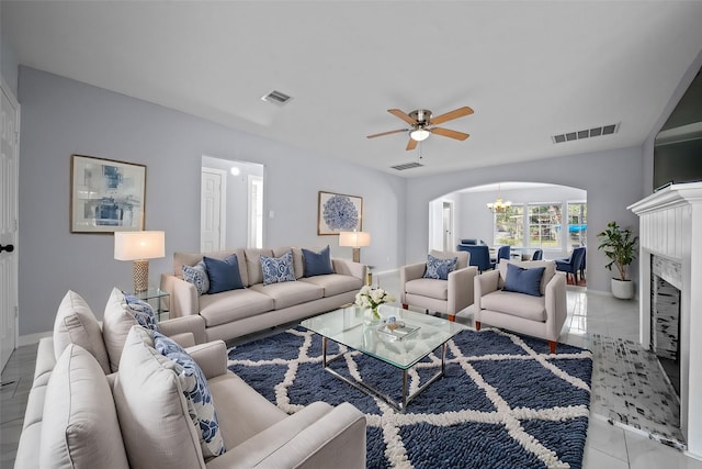 living room with a premium fireplace and ceiling fan with notable chandelier